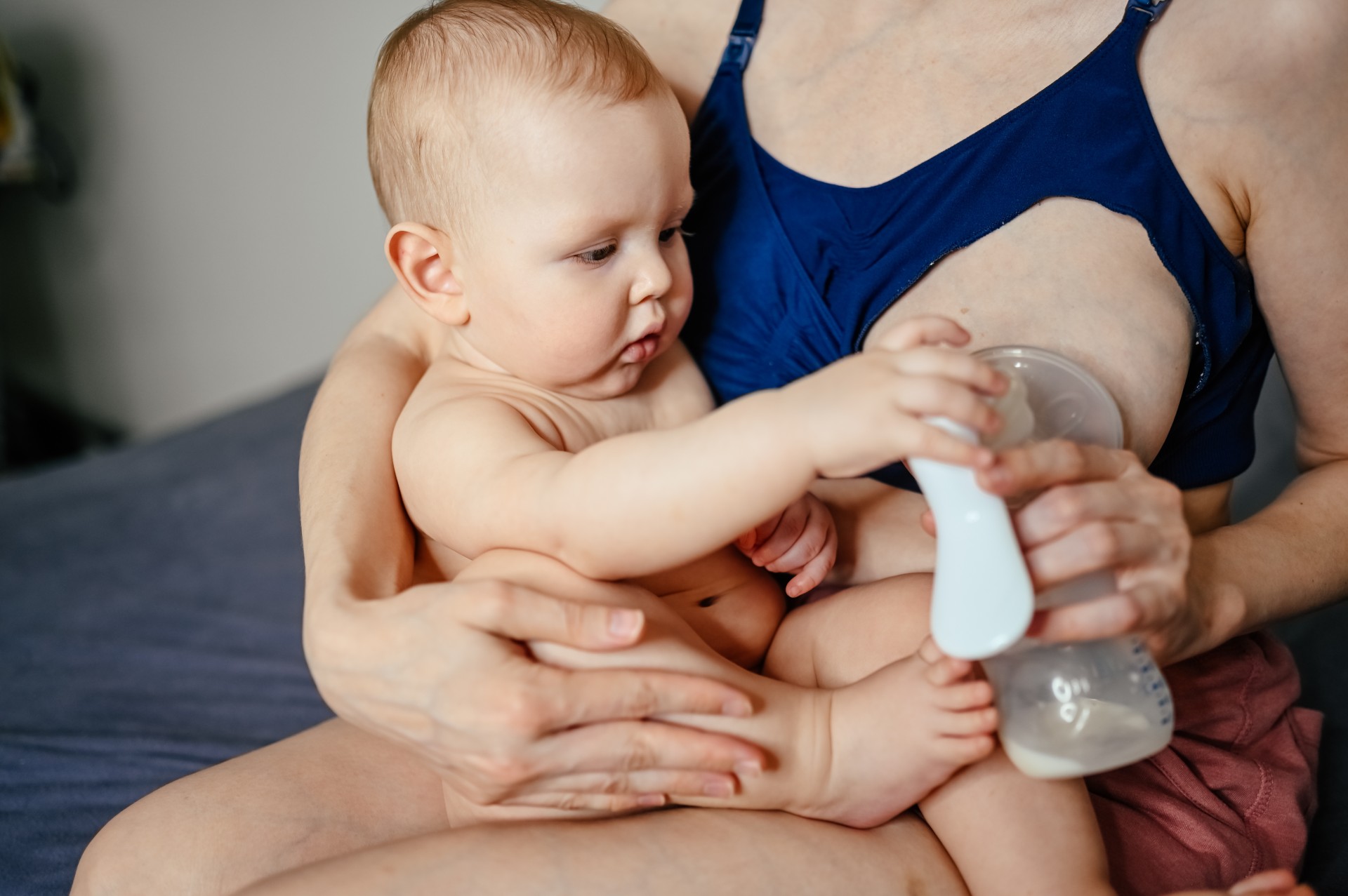 Frau pumpt Muttermilch ab, während das Kind auf dem Schoß sitzt